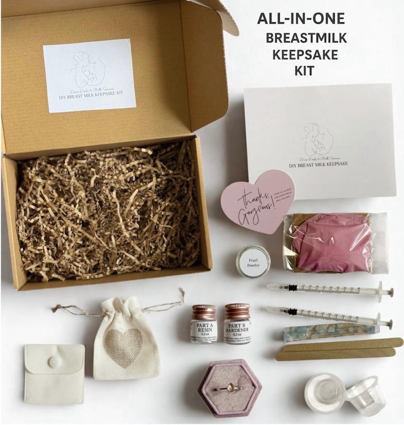 K&ouml;nnte beinhalten: Ein DIY-Muttermilch-Andenken-Kit mit verschiedenen Komponenten, die auf einer wei&szlig;en Oberfl&auml;che angeordnet sind. Das Kit enth&auml;lt Harz, Spritzen, eine Ringbox, einen kleinen Beutel mit einem Herz und eine herzf&ouml;rmige rosa Karte mit der Aufschrift "Thanks, Gorgeous!". Das Kit ist mit "ALL-IN-ONE BREASTMILK KEEPSAKE KIT" beschriftet.
