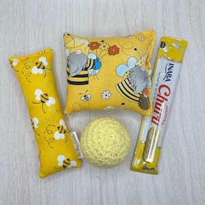 Puede incluir: Un conjunto de juguetes para gatos que incluye un juguete de tela con catnip amarillo y negro con temática de abejas, una pelota de crochet amarilla y una almohada de tela amarilla y negra con temática de abejas. El conjunto también incluye un paquete de golosinas para gatos INABA Churu de pollo con queso.