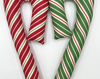 May include: Two fabric candy cane pillows, one red and white, one green and white, shaped into a heart.