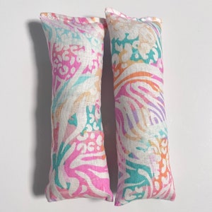 Puede incluir: Dos juguetes de tela para gatos con hierba gatera, con un patrón floral en tonos de rosa, turquesa y blanco.