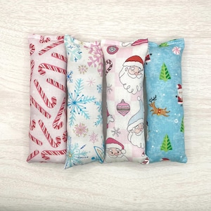 May include: Four festive catnip toys with different Christmas patterns. The toys are made of soft fabric and are filled with catnip. The patterns include candy canes, snowflakes, Santa Claus, and a Christmas tree.