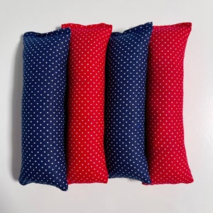 Puede incluir: Cuatro almohadas rectangulares de tela roja y azul marino, cada una con un estampado de lunares blancos. Las almohadas están dispuestas una al lado de la otra sobre un fondo blanco. La tela parece ser de algodón o lino tejido.