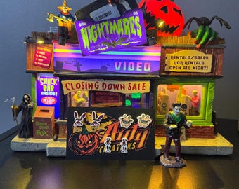 May include: A Halloween-themed video store diorama with a glowing pumpkin, a VHS tape labeled "Nightmares," and the text "Closing Down Sale." Includes miniature figures of a Grim Reaper and Frankenstein.