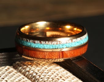 May include: A gold ring with a wooden inlay and turquoise and white accents.