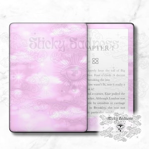 Peut inclure: Une liseuse Kindle Paperwhite rose et blanche avec une housse personnalisée représentant un ciel aquarelle rose et blanc avec des nuages et des étoiles. Le texte "Sticky Sadness" est imprimé sur la housse.