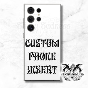 May include: White phone case with the words "CUSTOM PHONE INSERT" in black, stylized font. The case has a black border and a camera array at the top. A logo with a winged figure and the text "STICKY SADNESS" is in the bottom right corner.
