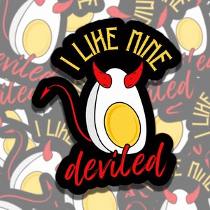 May include: A sticker featuring a deviled egg with devil horns and a tail. The text "I LIKE MINE deviled" is written in yellow and red. The background is a pattern of similar stickers.
