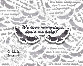 May include: A sticker with a black and white illustration of a bird with the text "We love rainy days, don't we baby?" and a smaller sticker with the text "Officially Licensed" in a cloud design.