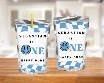 May include: Two silver pouches with blue and white checkered patterns. The text "SEBASTIAN IS ONE HAPPY DUDE" is printed on the front, along with a smiley face with lightning bolts. One pouch has a yellow straw.