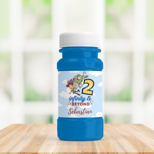 Op de afbeelding: Een blauwe bellenblaasfles met een witte dop. Het etiket toont de personages Woody en Buzz Lightyear, het nummer 2 en de woorden "infinity & beyond" en "Sebastian". De fles staat op een houten oppervlak.