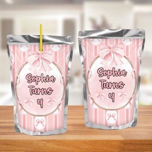 May include: Two pink and silver pouches with the text "Sophia Turns 4". The pouches have a pink bow and a pink and white striped background. One pouch has a yellow straw.