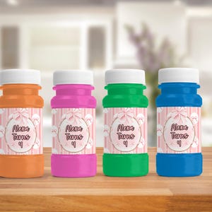 May include: Four colorful bubble bottles in orange, pink, green, and blue, each with a white cap. The bottles have labels with the text "Alexa Turns 4" in a decorative font, surrounded by a pink and white striped pattern.
