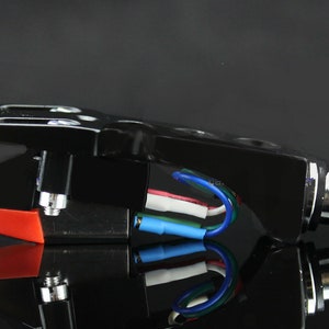 May include: Black phono cartridge with a red stylus and a silver connector with four gold pins. The cartridge has a black wire with blue, white, and red wires connected to it.