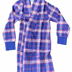 May include: A blue, pink, and white plaid robe with long sleeves and a shawl collar. The cuffs and collar trim are solid blue. The robe is made of a soft, comfortable material.