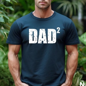 May include: A navy blue t-shirt with a white distressed graphic that says "DAD^2".