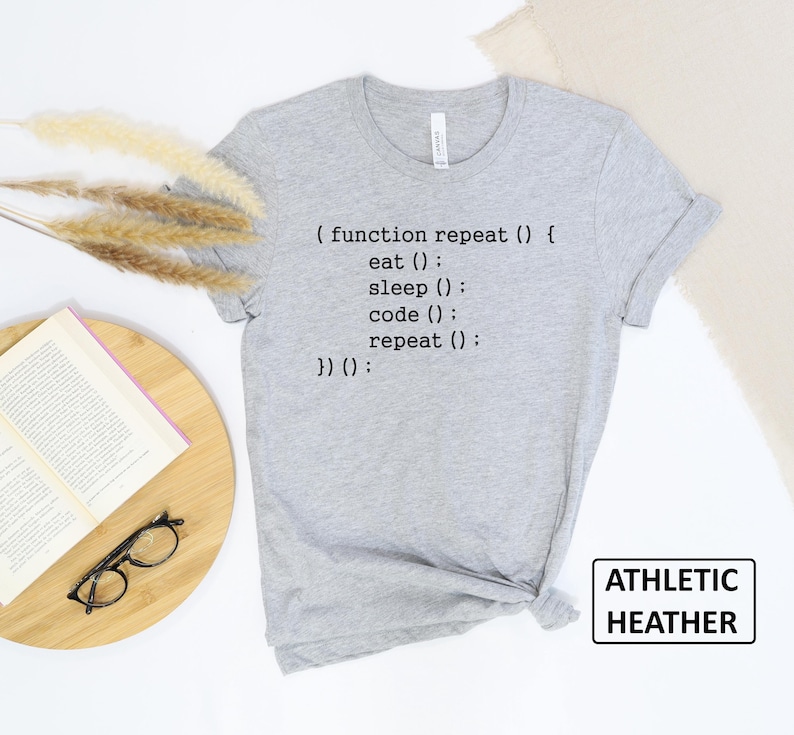May include: Athletic heather gray t-shirt with the text "(function repeat() { eat(); sleep(); code(); repeat(); })();". The shirt is a crew neck and has a tag that says "ATHLETIC HEATHER".