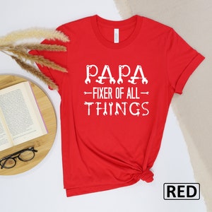 May include: Red t-shirt with white text that reads "Papa - Fixer of All Things" with wrench icons.