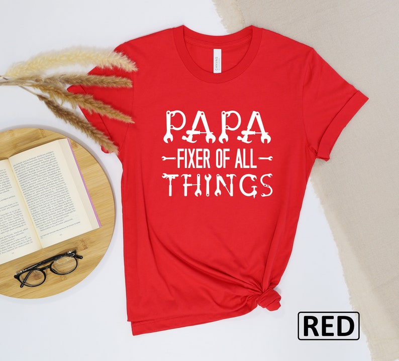 May include: Red t-shirt with white text that reads "Papa - Fixer of All Things" with wrench icons.