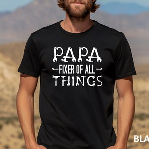 May include: Black t-shirt with white text that reads "Papa - Fixer of All - Things" with wrench and screwdriver graphics.