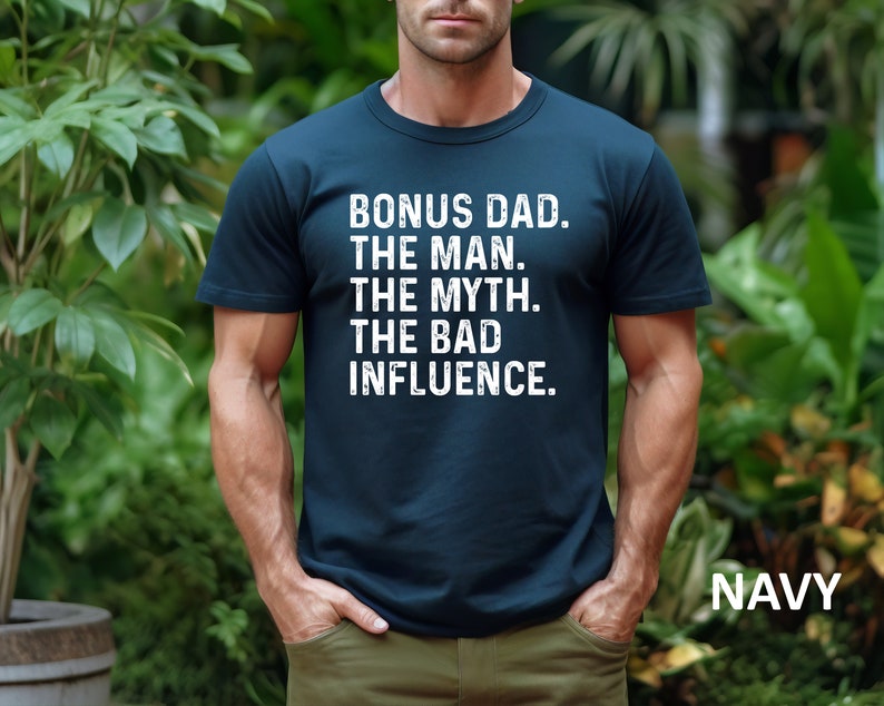 May include: A navy blue t-shirt with white text that reads "Bonus Dad. The Man. The Myth. The Bad Influence."