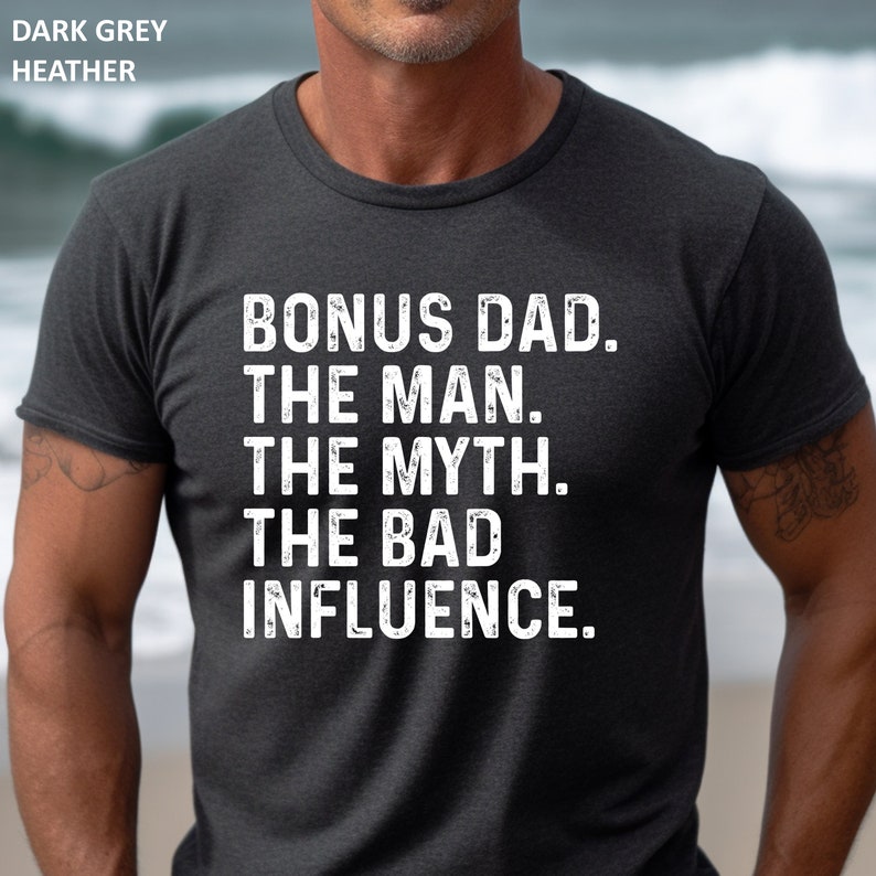 May include: Dark heather grey t-shirt with the text "BONUS DAD. THE MAN. THE MYTH. THE BAD INFLUENCE."