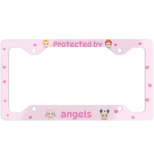 May include: A pink license plate frame with the text "Protected by angels." The frame has small pink hearts and cartoon angel figures. The frame is designed to fit a standard U.S. license plate.