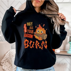 May include: Black hoodie with a graphic of a cartoon fire spirit holding a log, with the text "May all your bacon burn".