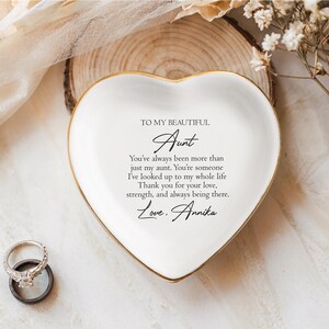 May include: White heart-shaped trinket dish with a gold rim. The dish has a message written on it that reads "To my beautiful Aunt You've always been more than just my aunt. You're someone I've looked up to my whole life. Thank you for your love, strength, and always being there. Love. Annika"