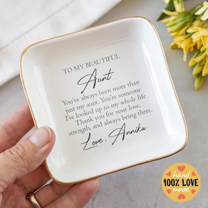 May include: White ceramic trinket dish with a gold rim. The dish has a message that reads "To my beautiful Aunt You've always been more than just my aunt. You're someone I've looked up to my whole life Thank you for your love, strength, and always being there. Love, Annika".