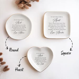 May include: Three ceramic trinket dishes in different shapes: round, heart, and square. Each dish has a gold rim and features a personalized message for an aunt, with the text "To my beautiful Aunt..." and a handwritten signature.