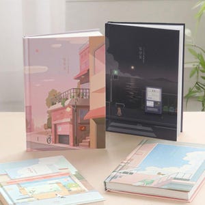 Op de afbeelding: Een verzameling notitieboekjes met geïllustreerde covers. Eén notitieboekje toont een roze en perzikkleurige gebouwenscène, terwijl een ander een nachtscène met een automaat afbeeldt. De andere notitieboekjes hebben vergelijkbare illustraties.