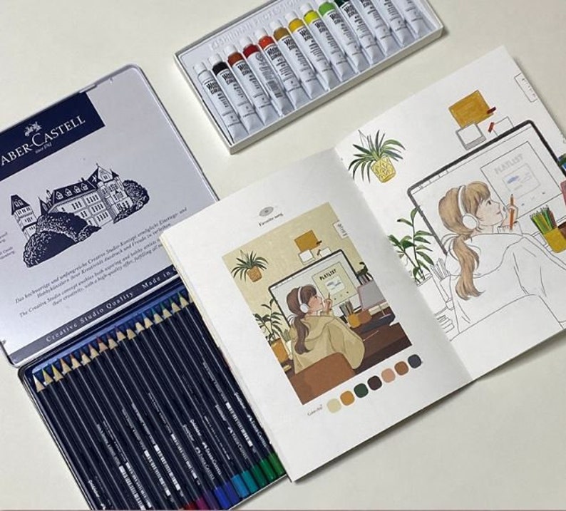 May include: A set of coloured pencils in a blue tin with the brand name Faber-Castell. The tin features a picture of a castle. The pencils are arranged in a row and labelled with their colours. The pencils are being used to colour a drawing of a person sitting at a desk with a computer. The drawing is in a sketchbook with a colour palette.