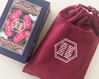 May include: A blue box with a floral design and the text "囍" in white. The box is sitting on a white surface next to a burgundy velvet pouch with the same text in white.