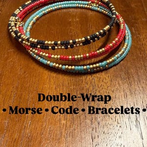May include: Three double-wrap bracelets made of small beads in black, red, and turquoise, each accented with metallic gold beads. The text "Double-Wrap Morse Code Bracelets" is printed below the jewelry in black lettering.