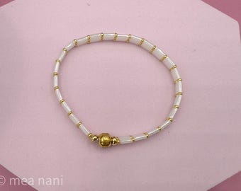 Elegant bracelet with white glass beads and gold-colored accents