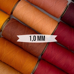 May include: Spools of waxed thread in various shades of orange, red, and brown. The thread is 1.0 mm thick.