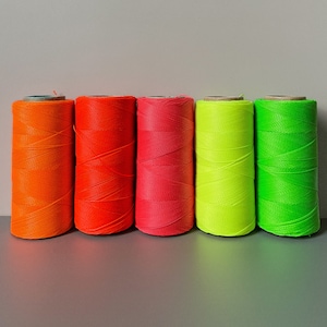 Könnte beinhalten: Fünf Garnrollen in verschiedenen Farben. Die Rollen sind orange, rot, rosa, gelb und grün.