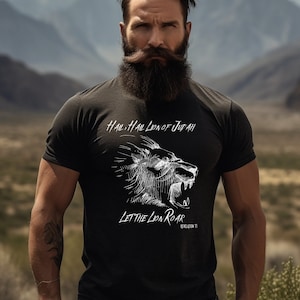以下が含まれることがあります： ライオンの頭が吠えている白いグラフィックがプリントされた黒いTシャツ。シャツには「Hail, Hail Lion of Judah」と「Let the Lion Roar」の文字がプリントされています。「Revelation 5:5」の文字もシャツにプリントされています。
