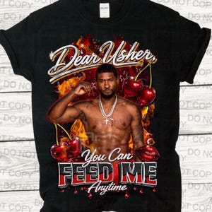 Może przedstawiać: Czarny t-shirt z grafiką Ushera, wiśniami i napisem "Dear Usher, You Can Feed Me Anytime." Projekt zawiera czerwony i biały tekst na tle płomieni.
