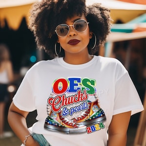 May include: White t-shirt with a colorful graphic of a pair of sneakers with the text "OES Chucks & pearls 2024" on it.