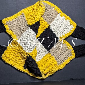 May include: A crocheted tote bag made with black, yellow, white and beige yarn. The bag features a diamond pattern and two black straps.