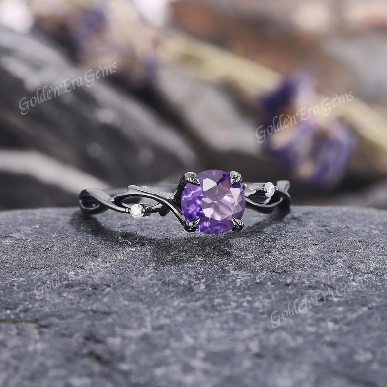 May include: A black gold ring with a purple amethyst gemstone and small white diamonds set in a vine-like design.