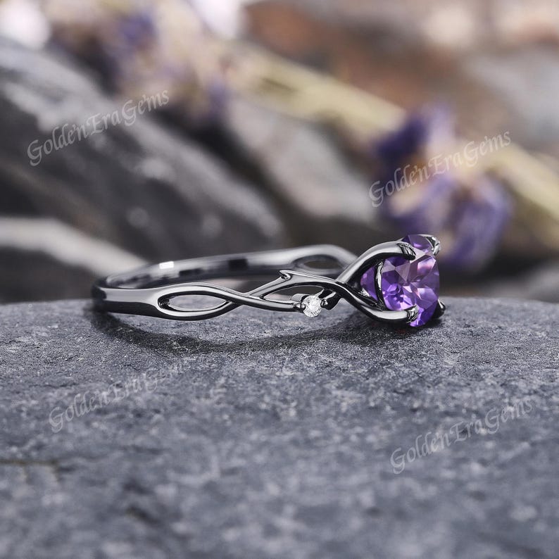 May include: Black gold ring with a purple heart-shaped amethyst gemstone and small diamond accents. The ring band is a delicate, twisted vine design.