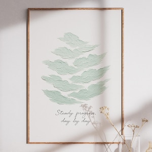 May include: A framed art print with a light green cloud design. The artwork includes the text "Steady progress, day by day" in a cursive font. The frame is a light brown colour.
