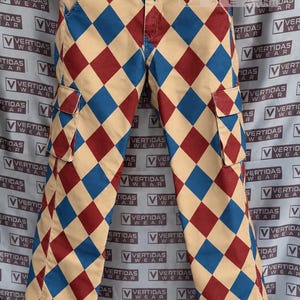 Peut inclure: Pantalon cargo arborant un motif à losanges répétitif en beige, rouge foncé et bleu. Le pantalon comprend une fermeture à bouton à la taille, des passants de ceinture et deux poches cargo latérales à rabat. Le motif couvre tout le devant.