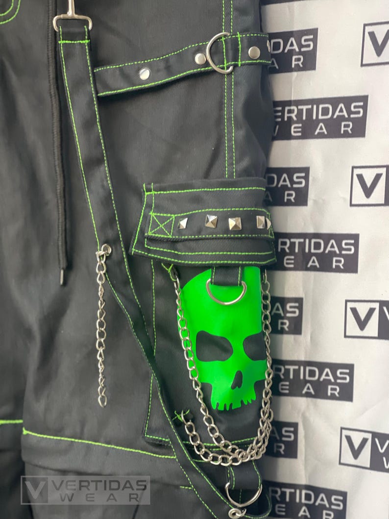 May include: Black pants with green stitching and a skull patch. The pants have multiple straps and buckles. The pants are labeled "VERTIDAS WEAR".