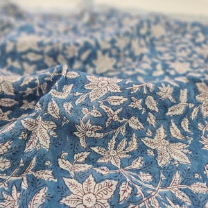K&ouml;nnte beinhalten: Blauer Baumwollstoff mit einem wei&szlig;en und roten Blumendruck. Der Stoff ist weich und texturiert und eignet sich perfekt f&uuml;r Bastel- oder N&auml;hprojekte.