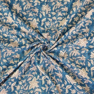 K&ouml;nnte beinhalten: Blauer Stoff mit einem wei&szlig;en Blumenmuster. Der Stoff ist gefaltet und zeigt das sich wiederholende Muster.
