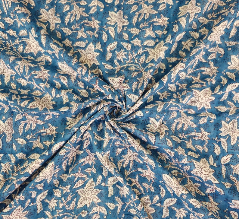 K&ouml;nnte beinhalten: Blauer Stoff mit einem wei&szlig;en Blumenmuster. Der Stoff ist gefaltet und zeigt das sich wiederholende Muster.
