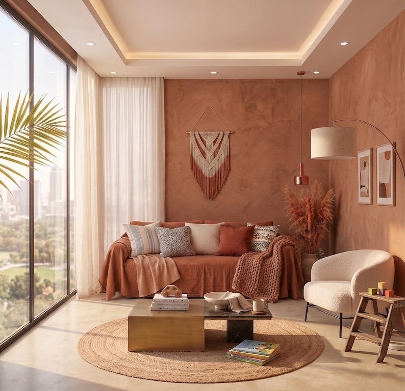 May include: A living room featuring a terracotta-colored sofa with various throw pillows and a knit blanket, a square metallic coffee table, a cream-colored armchair, a wooden step stool, a macrame wall hanging, and a round jute area rug.